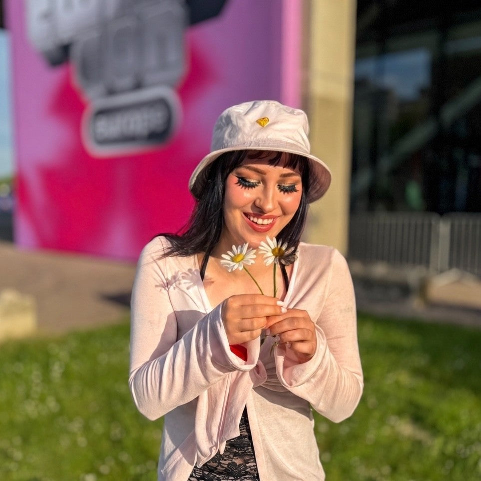 a member of G's community smiling down at a daisy in the pizzaaaaaheartpizza bucket hat at TwitchCon Europe