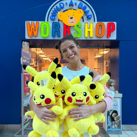 G hugging an armful of Pikachu plushes outside a Build-A-Bear Workshop