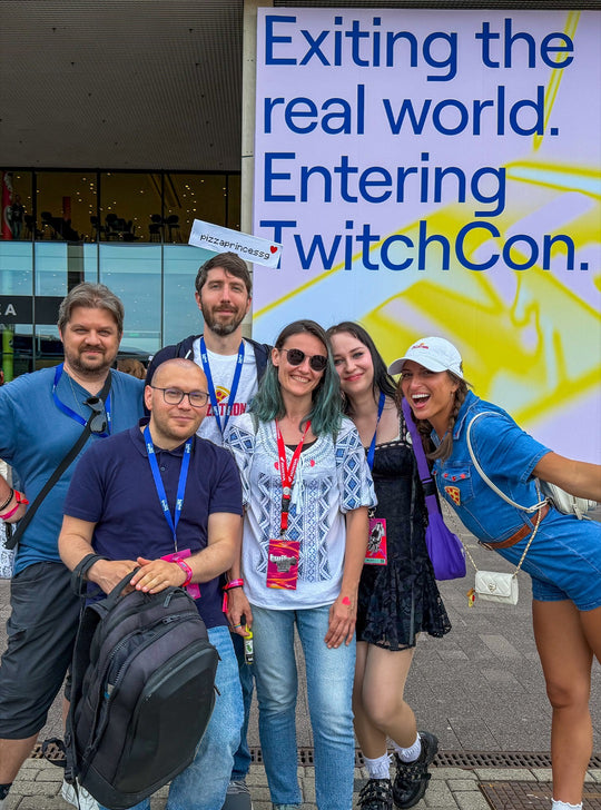 G and five members of the PPG unit grinning in front of the TwitchCon Europe sign, one holding a pizzaprincessg sign