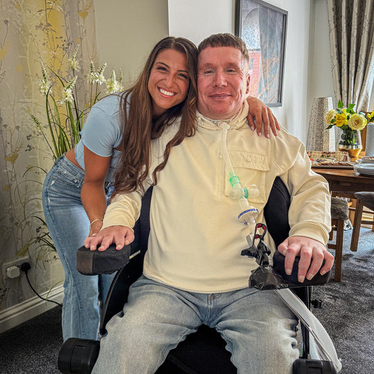 G with an arm around a friend seated in a wheelchair
